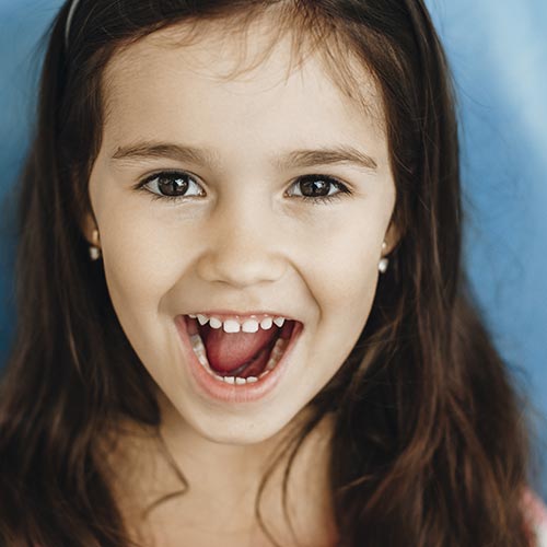 little girl showing teeth after sealant therapy