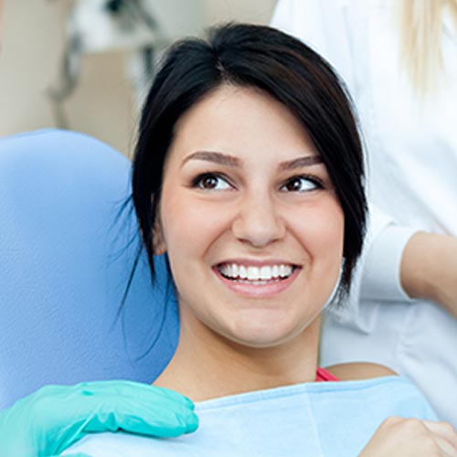 smiling woman being treated by dental hygienist as a part of general dentistry in Mississauga