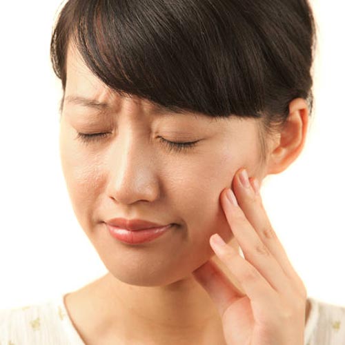 woman with sudden pain holding cheek
